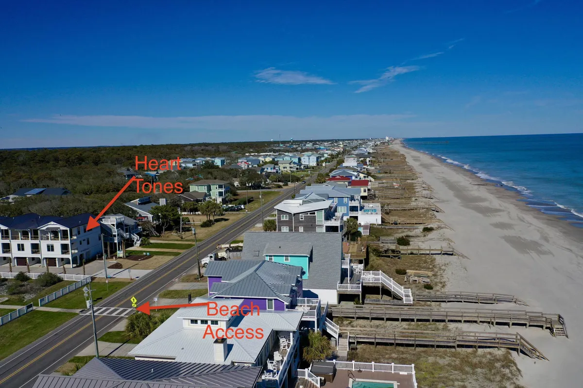 A serene exterior shot showing the road leading directly to the beach, flanked by coastal homes and open skies. The image captures an early morning or late afternoon light, highlighting the ease of access to the ocean and the tranquil ambiance of the area.