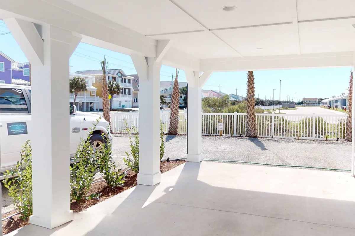 A view of the inviting porch framed by white pillars, green plants, and a clear path leading to the entrance and nearby road. The approachable design and open space underline accessibility and a friendly, inclusive atmosphere.
