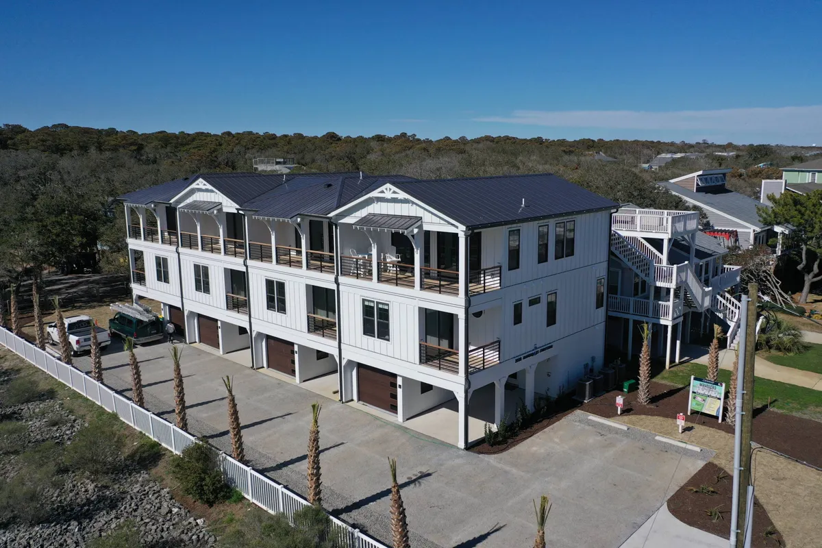 This exterior image showcases the multi-story building with visible balconies, palm trees, and a driveway, emphasizing the welcoming and accessible entry points. The covered parking area and wide driveway are clearly visible, reinforcing comfort and ease of entry in any weather for guests of all ages.