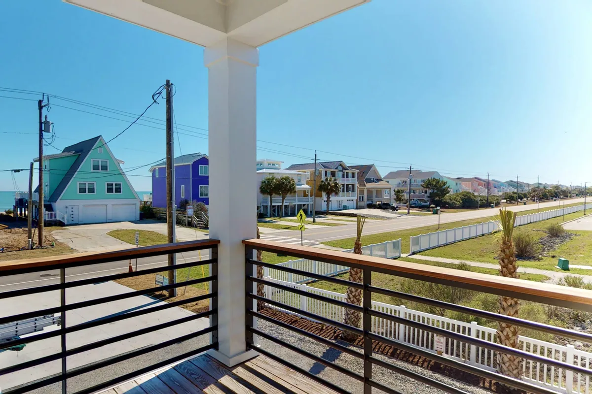 This image shows a lively beachside street lined with colorful houses, palm trees, and a clear view of the beach. The inviting atmosphere is ideal for family strolls, social gatherings, or enjoying sunrise coffee on the balcony.