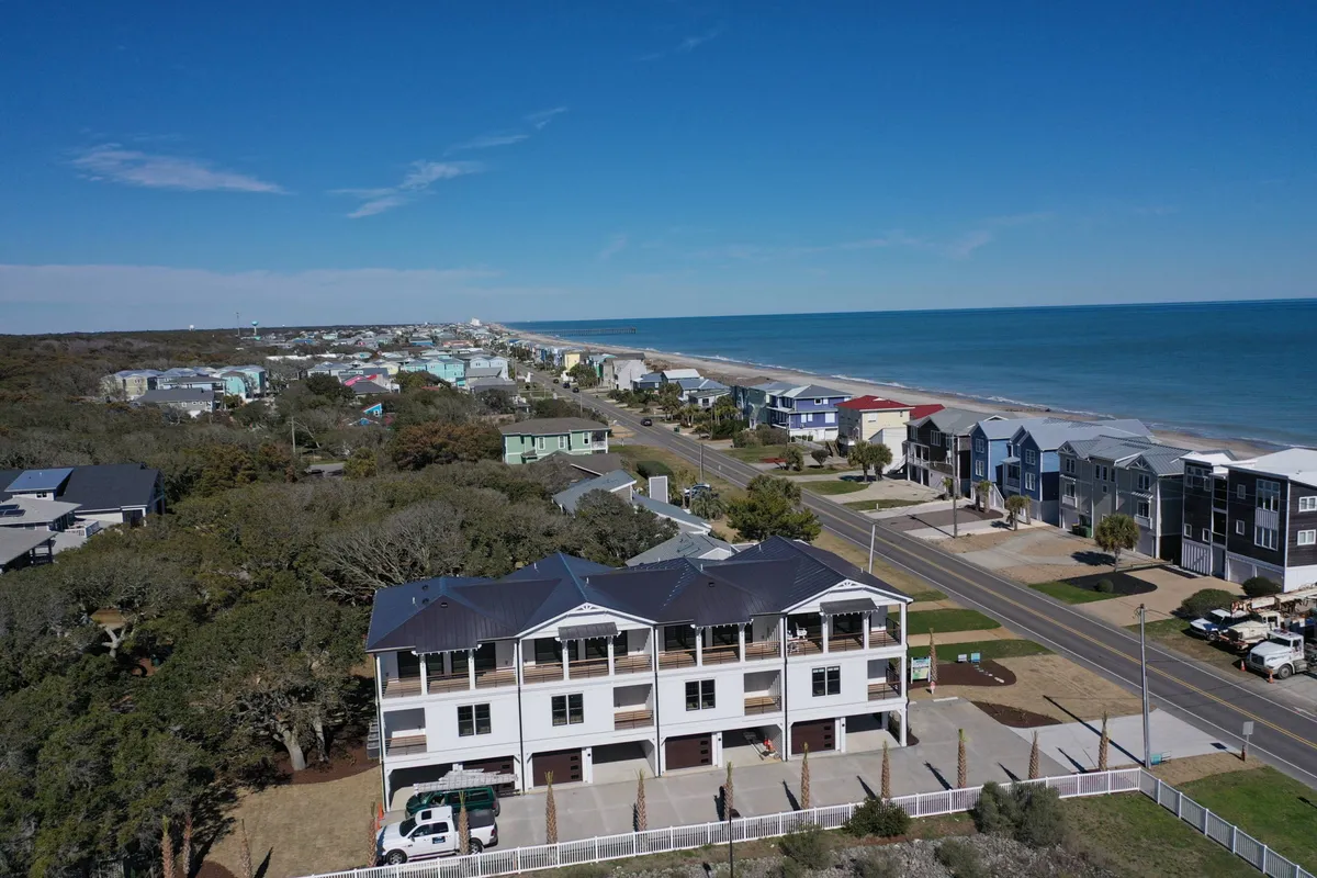 A coastal road flanked by beachfront homes, with the ocean visible just beyond. The scene suggests easy access to biking along the coast, beachcombing, and exploring local shops—activities that align with the section’s encouragement to get out and explore Pleasure Island by bike or golf cart.