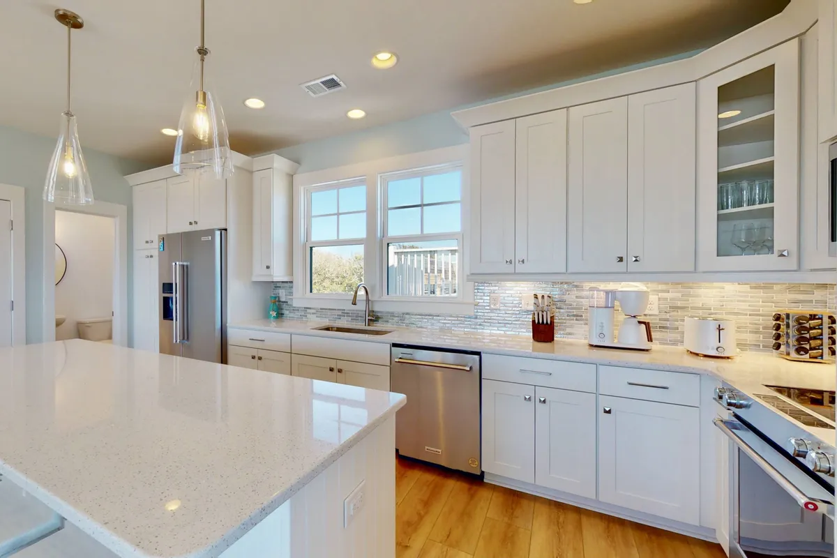 A modern laundry and kitchen area with a prominent island countertop, stainless steel appliances, and ample natural light through a window. The scene is both functional and inviting, suggesting convenience for everyday living.