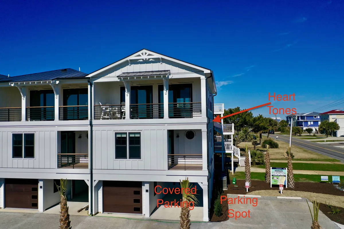 The exterior shot highlights the home's modern architecture, covered parking area, and inviting balcony seating. The covered parking is directly visible, visually connecting the garage interior with its practical exterior access and shelter for vehicles and equipment.